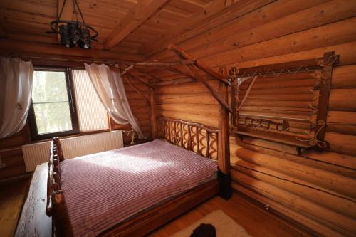a bedroom in a log cabin with a bed in it at Приватна садиба Дикий Мед in Ploskoye