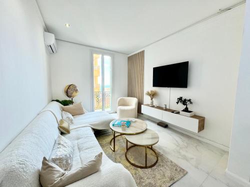 ein weißes Wohnzimmer mit einem Sofa und einem TV in der Unterkunft Appartement vue mer vue Monaco in Beausoleil
