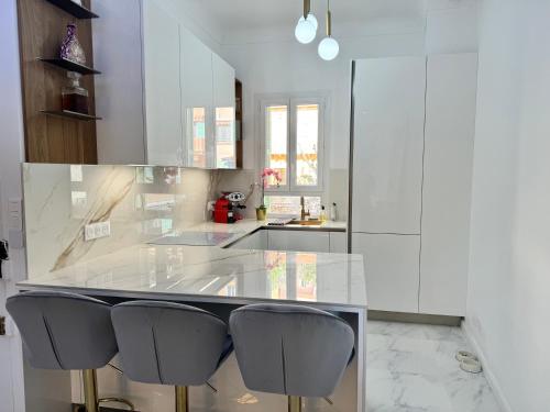 eine Küche mit weißen Schränken und einer Theke mit Stühlen in der Unterkunft Appartement vue mer vue Monaco in Beausoleil