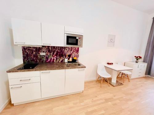 a white kitchen with a table and a microwave at Helen Homestay 50m from Wenceslas Square in Prague