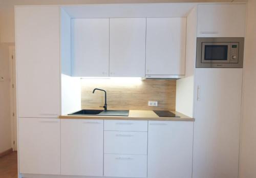 una cucina bianca con un lavello e un forno a microonde di Casa Rural Sierra Morena a Cazalla de la Sierra