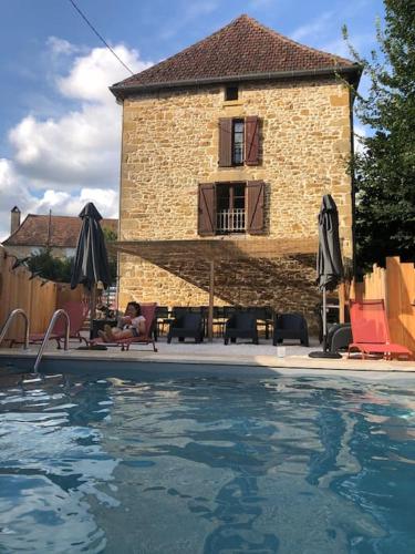 une personne assise sur une chaise à côté d'une maison avec piscine dans l'établissement Maison Vacances 12 pers / Périgord Noir / Piscine, à Saint-Julien-de-Lampon