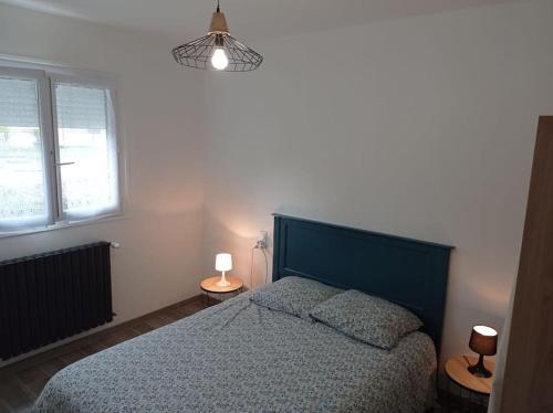 une chambre avec un lit avec une tête de lit bleue et deux lampes dans l'établissement Maison de vacances Morbihan, à Landaul