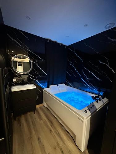 La salle de bains est pourvue d'une baignoire, d'un miroir et d'un lavabo. dans l'établissement Dark Room BLOIS - Love Room, à Saint-Gervais-la-Forêt