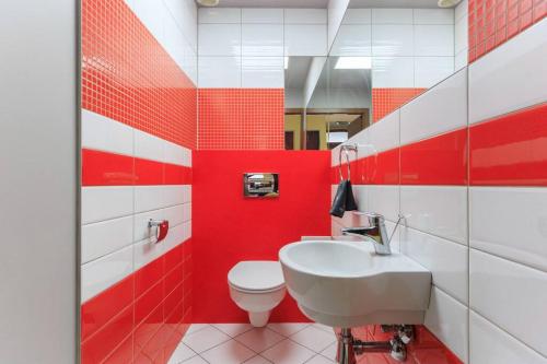 a red and white bathroom with a toilet and a sink at Apartament w sercu Katowic in Katowice