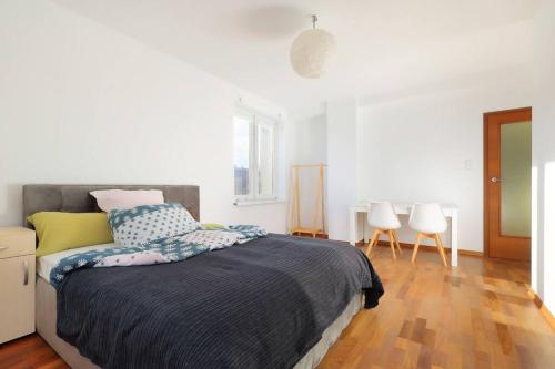 a white bedroom with a bed and two chairs at Apartament w sercu Katowic in Katowice