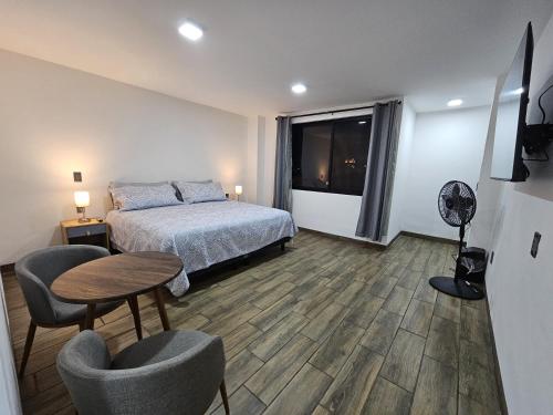 1 dormitorio con 1 cama, mesa y sillas en Estancia Real en Morelia