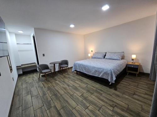 a bedroom with a bed and two chairs and a table at Estancia Real in Morelia