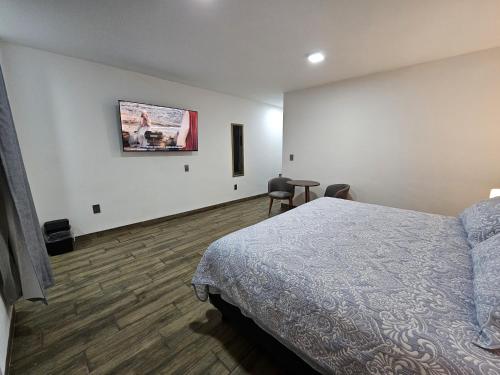 a bedroom with a bed and a tv on the wall at Estancia Real in Morelia