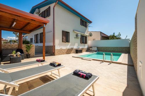 un patio trasero con piscina y una casa en Villa DellOmbra, en Alcamo