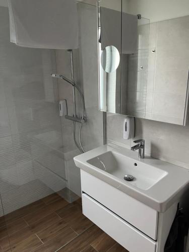 biała łazienka z umywalką i prysznicem w obiekcie Napfény Apartman ll. w mieście Sopron