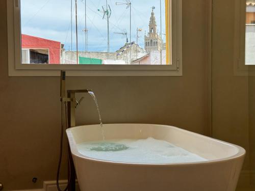 una vasca da bagno con acqua che esce da una finestra di Luxury Cathedral Views in Sevilla a Siviglia