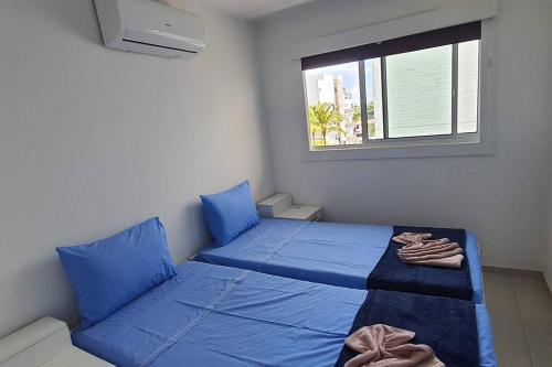 a bedroom with a blue bed and a window at Condomínio Porto de Soleil in Porto De Galinhas