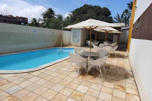 a patio with a table and umbrella next to a pool at Condomínio Porto de Soleil in Porto De Galinhas