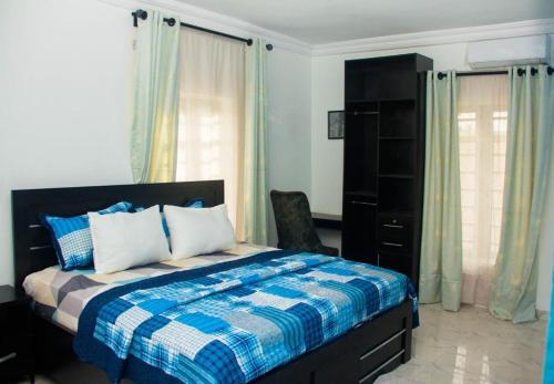 a bedroom with a bed with a blue and white blanket at 3Tee Serviced Apartment Abeokuta in Abeokuta