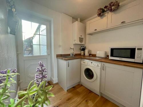 eine Küche mit einer Waschmaschine und einer Mikrowelle in der Unterkunft Mulberry Annexe in Felixstowe