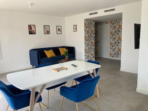 ein Esszimmer mit einem weißen Tisch und blauen Stühlen in der Unterkunft Maison tout confort in Cambo-les-Bains