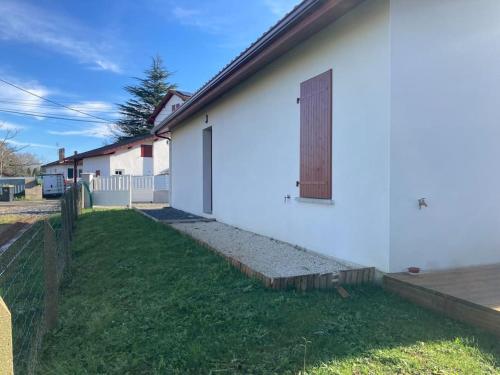ein weißes Gebäude mit einer Seitentür in der Unterkunft Maison tout confort in Cambo-les-Bains