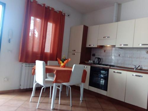 a kitchen with a table and some white chairs at Casa di Cristina in Fiumicino