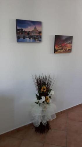 a vase of flowers in a white wall with two pictures at Casa di Cristina in Fiumicino