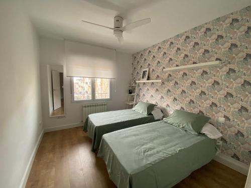 een slaapkamer met 2 bedden en een muur met bloemen bij APARTAMENTO RECONQUISTA in Toledo