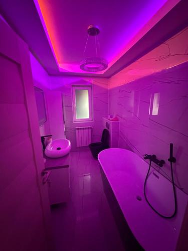 Cette chambre violette comprend une baignoire et un lavabo. dans l'établissement Apartament Chloe, à Tulcea