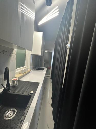 a kitchen with a sink and a black stove at Apartament Chloe in Tulcea