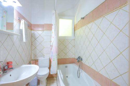 a bathroom with a sink and a toilet and a tub at Mare Vista Ariadni in Nisakion
