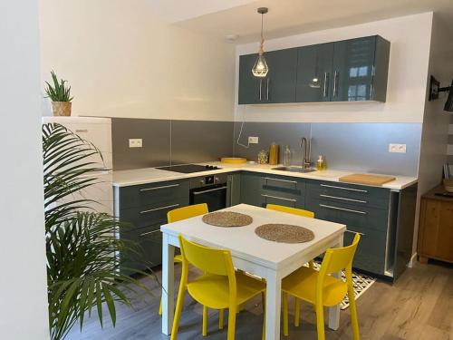 une cuisine avec une table blanche et des chaises jaunes dans l'établissement Dole : studio en plein centre, copropriété calme, à Dole