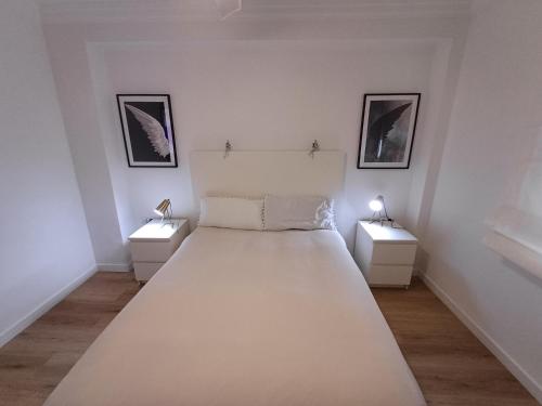 um quarto branco com duas mesas de cabeceira e uma cama em MATISSE em Sevilha