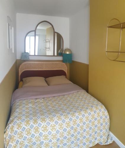 - une chambre avec un lit et un miroir au-dessus dans l'établissement Flut'Alors - Maison charmante au centre-ville de Reims, à Reims