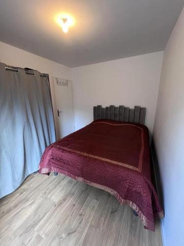 une chambre avec un lit avec une couverture rouge dessus dans l'établissement Appartement 5 personnes, à Pierrefitte-sur-Seine