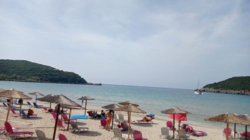 a group of people sitting on a beach with umbrellas at Acheron rooms in Preveza