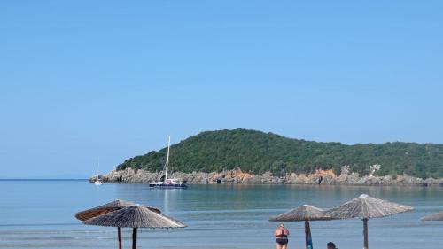 a beach with umbrellas and a boat in the water at Acheron rooms in Preveza