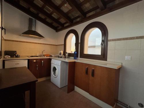 a kitchen with a washing machine and a window at Posada Alegria in Medina Sidonia