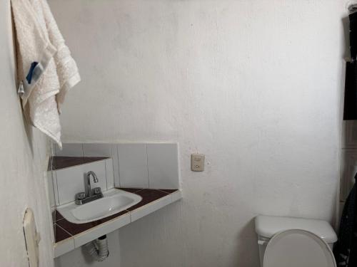 La salle de bains blanche est pourvue d'un lavabo et de toilettes. dans l'établissement LA VILLA DE LA ABUELA, à San Cristóbal de Las Casas