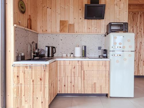 a kitchen with wooden cabinets and a white refrigerator at Chaty w chmurach in Komańcza