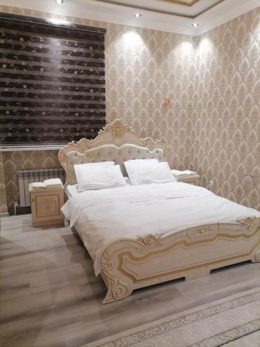 Un dormitorio con una gran cama blanca y una pared en Rudakiy Apartment, en Samarkand