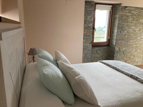 1 dormitorio con cama con almohadas y ventana en La Casina de Tano (Playa Tauran) en Luarca