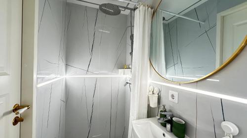 ein weißes Badezimmer mit einem Spiegel und einem Waschbecken in der Unterkunft Elegant Central park Apartment in Daugavpils