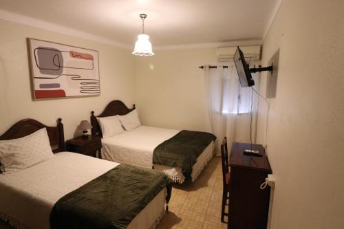 a hotel room with two beds and a television at Residencial Miguel José in Estremoz