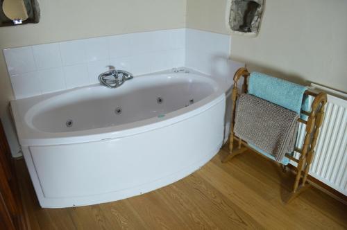 a white bath tub in a room with a chair at Love Cottage in Bell Busk