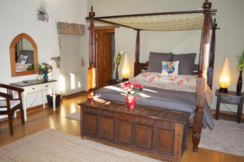 een slaapkamer met een hemelbed en een tafel met bloemen erop bij Love Cottage in Bell Busk