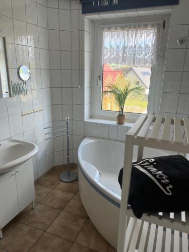 La salle de bains est pourvue d'une baignoire, d'un lavabo et d'une fenêtre. dans l'établissement Simsongarage Mönchswalde, à Obergurig