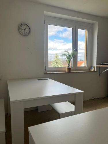 une table blanche et une fenêtre avec une horloge dans l'établissement Simsongarage Mönchswalde, à Obergurig