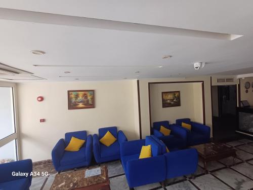 uma sala de espera com cadeiras azuis e almofadas amarelas em Palm Inn City Hotel em Hurghada
