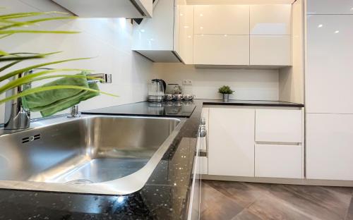 una cucina con lavello in acciaio inossidabile e mobili bianchi di Bellami Ferienwohnungen a Minden