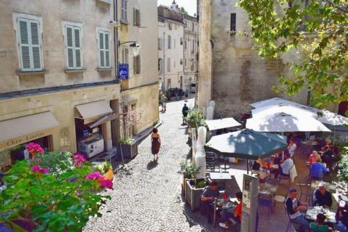 a group of people sitting at tables and umbrellas on a street at Centre Palais des Papes B2 Clim - 123Avignon in Avignon