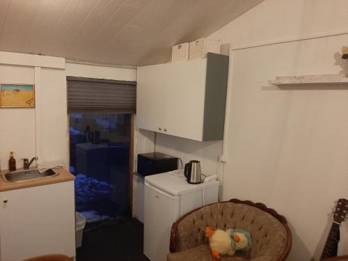 a kitchen with a refrigerator and a stuffed animal on a chair at Guesthouse Holmur in Hólmur