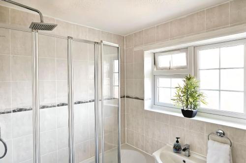 uma casa de banho com um chuveiro e um lavatório. em 4 Bedroom Spacious Entire House Sleeps 6 em Great Parndon